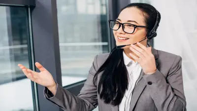 uma mulher branca, cabelo liso preto com fone de ouvido, falando com alguém e apontando a mão